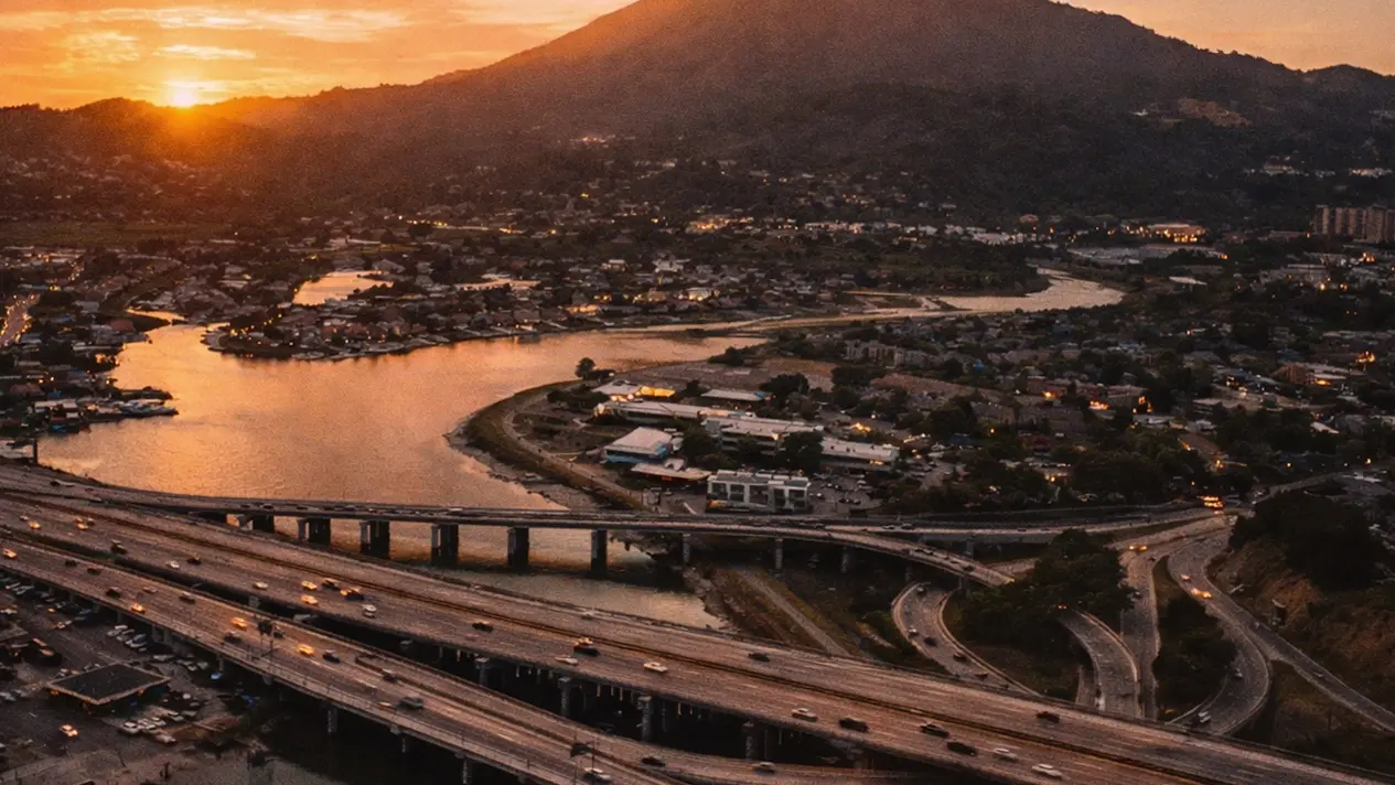 Sunset aerial over Corte Madera Creek, the Highway 101 interchange with evening traffic, and Mount Tamalpais on the horizon